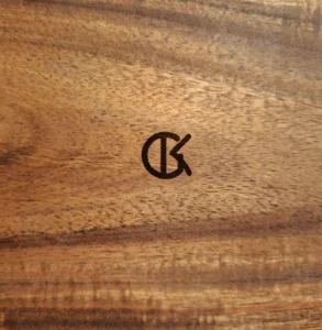 Het GK gegraveerd op hout.