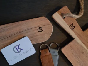 GK-merkteken van De Graveerkamer gegraveerd op een houten serveerplank en leren sleutelhanger